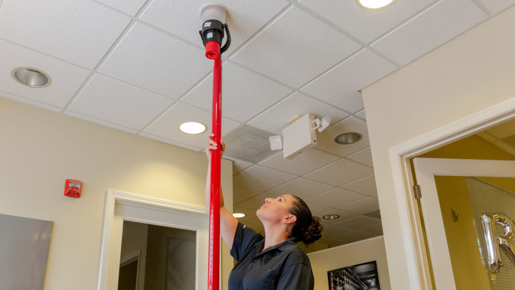 female testing a smoke detector using the solo 330 aerosol dispenser attached to a red solo pole
